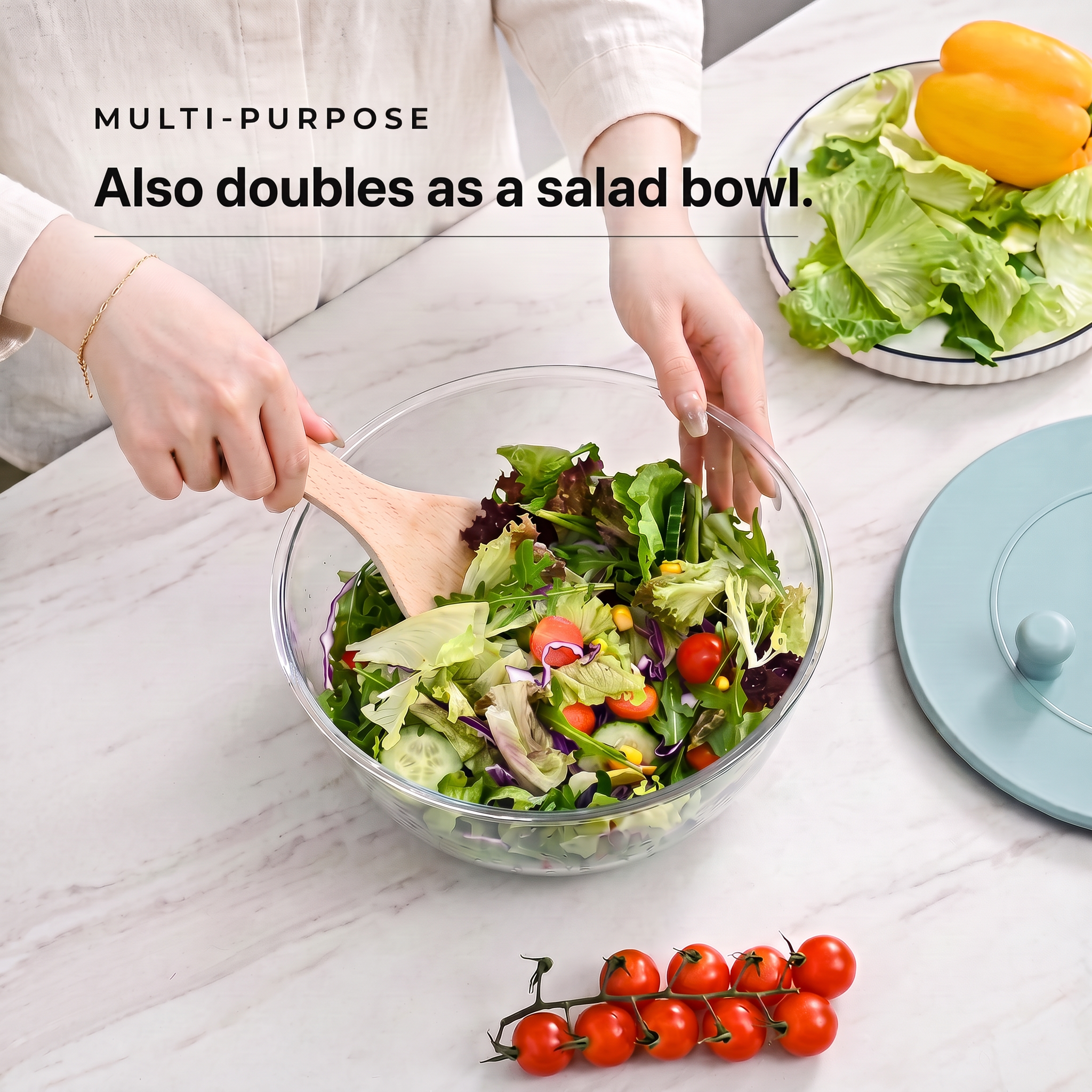 Clear PrepLoop bowl used as a salad bowl, tossing mixed greens with a wooden spoon